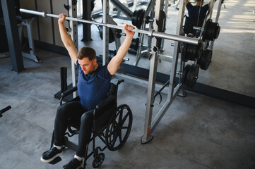 Man with disability lifting weights in wheelchair at gym for rehabilitation
