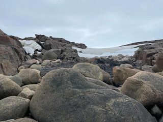 Huge stones and snow on the Dragon Beach on the shore of the Barents Sea. Teryberka, Russia