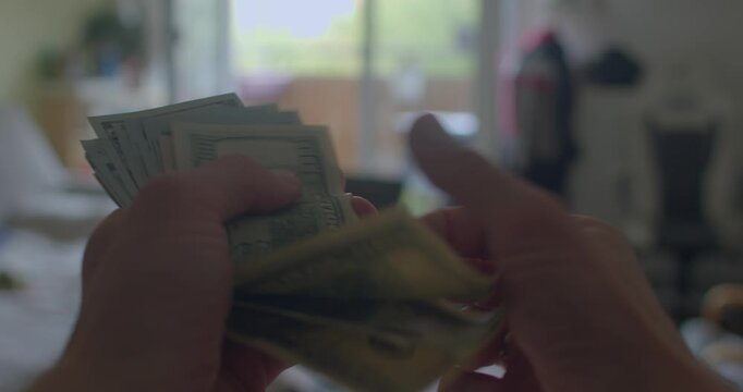 In a welllit room, an individual methodically counts a significant pile of cash, illustrating the multitude of currency transactions and financial exchanges occurring in their surroundings - Powered by Adobe