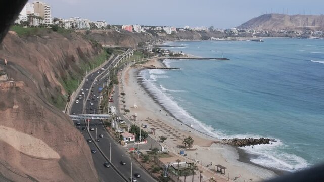 Paraglider flying over the miraflores district coastline, lima, peru, with the morro solar in the background