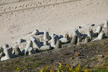 Stacked, reinforced, multi-arm concrete blocks separate dunes from the sand beach in Mielno, Poland