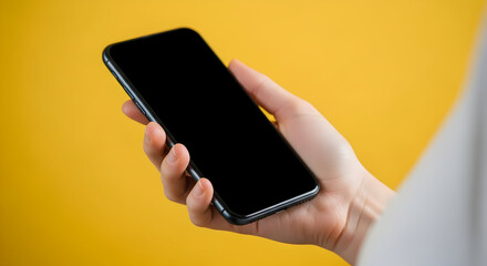Close-up of a hand holding a blank smartphone against a bright yellow background, perfect for showcasing apps or digital content