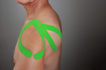 Older Man wearing Kinesio tape on his shoulder for pain relief 