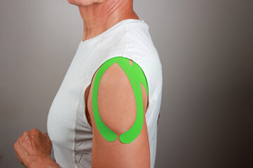 Older Man wearing Kinesio tape on his shoulder for pain relief 