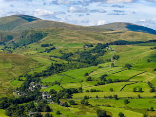 Aerial drone view of rolling green fells and patchwork farmland in Lake District, England