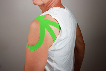 Older Man wearing Kinesio tape on his shoulder for pain relief 
