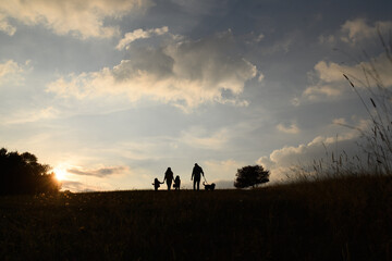 Silhouette of family with two small children in autumn nature at sunset.