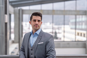Fototapeta premium Young businessman in suit standing indoors in an office.
