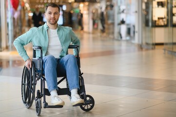 Obraz premium Customer using wheelchair moving in shopping mall corridor