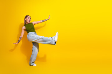 Cheerful young woman in a stylish casual outfit expressing joy against a bright yellow background