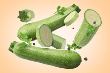 Fresh zucchinis, parsley and peppercorns falling on beige gradient background