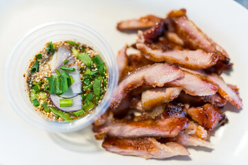 Grilled pork neck with spicy dipping sauce, showcasing traditional and flavorful Thai dish