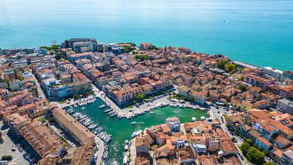 Aerial view of Grado, a picturesque seaside town in Friuli Venezia Giulia, Italy. The photo shows the historic old town with red-tiled roofs, charming harbor, long sandy beaches, blue water
