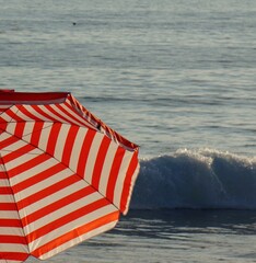 White and red striped sun umbrella on the beach with ocean 