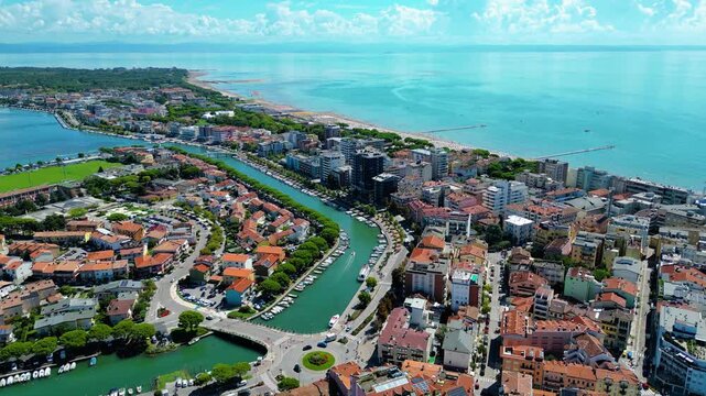 Aerial view of Grado, a picturesque seaside town in Friuli Venezia Giulia, Italy. The photo shows the historic old town with red-tiled roofs, charming harbor, long sandy beaches, blue water