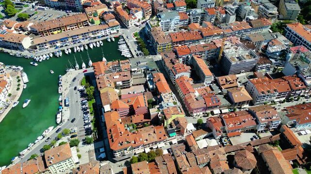 Aerial view of Grado, a picturesque seaside town in Friuli Venezia Giulia, Italy. The photo shows the historic old town with red-tiled roofs, charming harbor, long sandy beaches, blue water