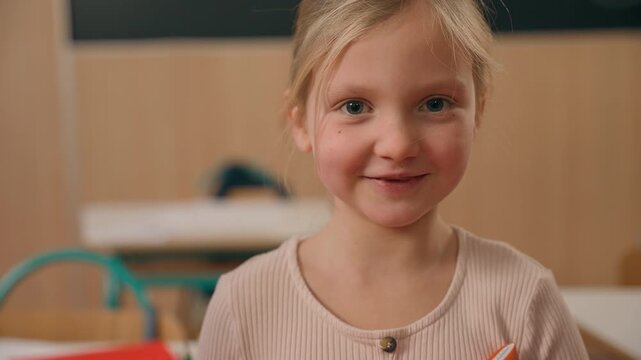 Close up portrait cute little Caucasian girl posing in primary school kindergarten studying looking at camera kid daughter child baby pupil look smiling without teeth dental oral pediatric health