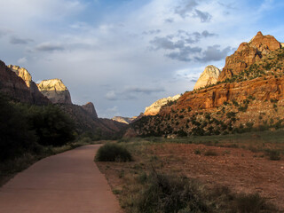 The Pa’rus Trail with majestic mountains of Zion Canyon, rising on either side of it with the peaks catching the last golden light of the afternoon, in Utah, USA.