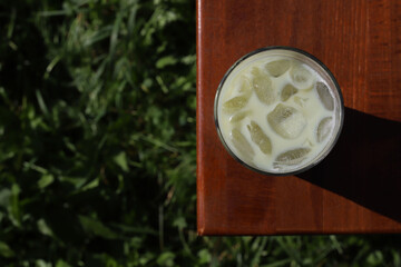 green matcha tea with ice on a wooden chair in the green nature