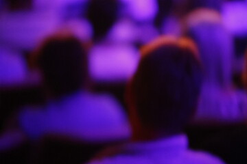 Image floue d'un groupe de personnes dans une salle de conférence.