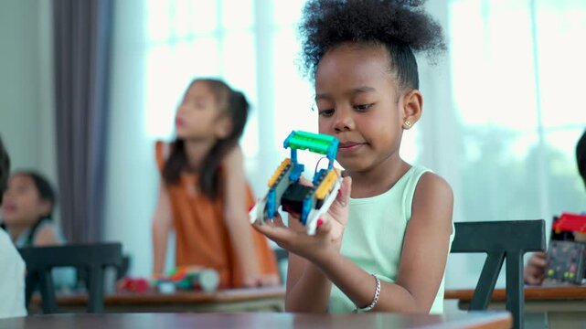 Elementary kids enjoying STEM class, building robots and coding with teacher.