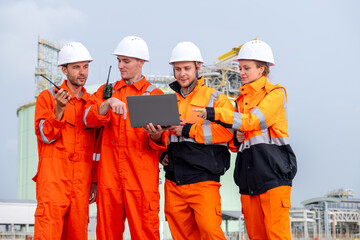 Team of workers in orange jumpsuits collaborating on a construction site during the day