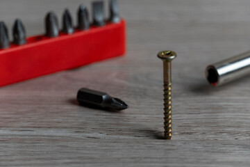 Close-Up of Screwdriver Bits and Screw on Wooden Surface