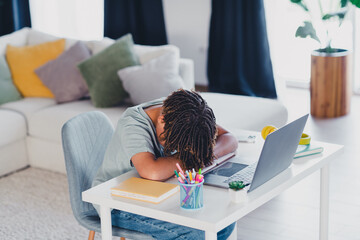 Young Student Napping at Home Desk with Laptop and Study Materials in Bright Living Room Environment