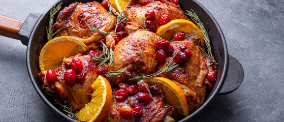 Christmas baked chicken with cranberries and oranges on grey background close up