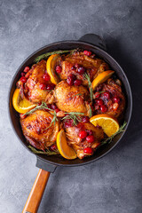 Christmas baked chicken with cranberries and oranges on grey background