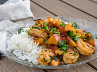 Plate of shrimp, peaches and rice on a wooden deck table