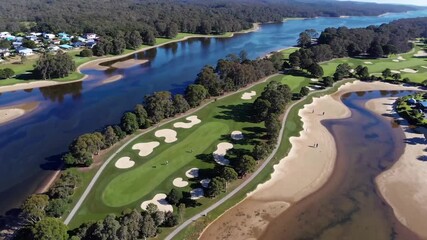 waterway meandering through regional terrain near coastal settlement, passing golfing facility on island