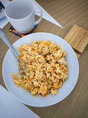 Chicken and rice dish pilaf served on white plate with mug nearby