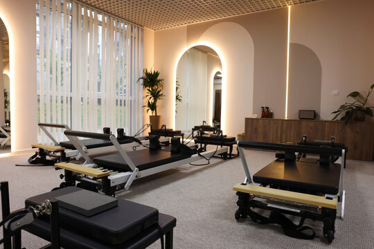 Many reformer machines in studio. Pilates equipment