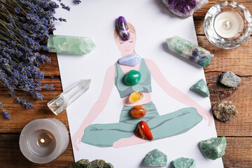 Human drawing with gemstones placed on chakras, lavender flowers on wooden table, flat lay