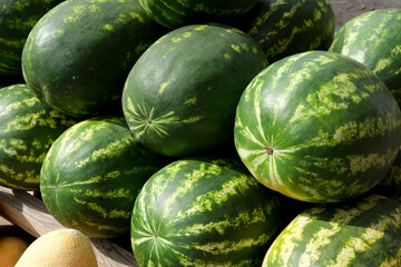 Fresh watermelons piled high at a vibrant farmers market