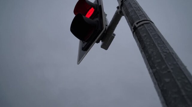 Detailed view of signal lamp at intersection displaying crimson indication for forward movement yet verdant arrow permitting solely right turn on chilly winter day with overcast heavens