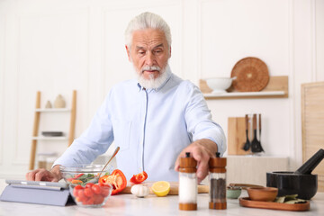 Elderly man cooking at white marble table in kitchen