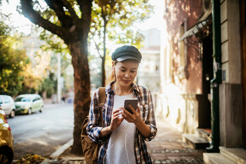 Young woman walking down a city street and using a smart phone