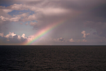 A Beautiful and Serene Rainbow is Arching Gracefully Over the Calm and Peaceful Oceanic Waters