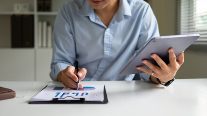A man's hand is checking a business plan from a piece of paper held in a clipboard.