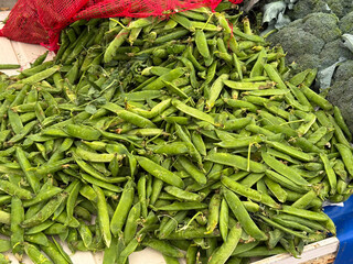 Green peas in pods spread across market stall surface. Agriculture, farming, and seasonal legume harvest with nutrition and healthy lifestyle.