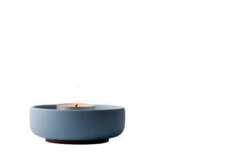  small lit candle floats serenely in blue bowl isolated on white background