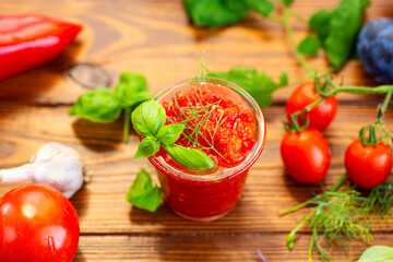 Glass of tomato sauce surrounded by garlic vegetables