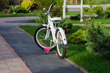 bicycle in the parkA bicycle stands on a green lawn surrounded by colorful flowers and lush trees under soft daylight