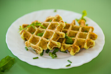 Vegetarian zucchini waffles served on a green surface