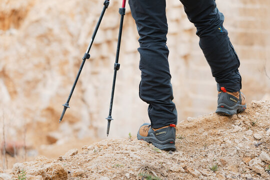 19 April 2025, Taor, Serbia: Close up view of hiking boots and trekking poles resting on a rocky mountain path