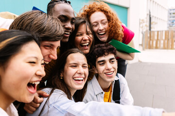 Portrait of happy diverse teenage students standing over isolated blue background