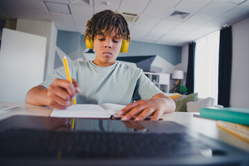Focused young boy wearing headphones studying indoors in a comfortable home environment, reflecting determination and learning