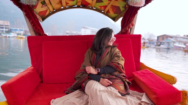 Beautiful Indian woman enjoying Shikara ride in Dal Lake at Srinagar, Jammu and Kashmir, India. Travel and holidays background. Female travel blogger enjoying boat ride during vacation. Travel concept